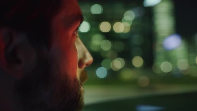 慢镜头近距离观察英俊的商人在一辆现代汽车旅行期间，一个司机在市中心的夜晚。