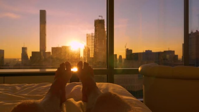 POV: 躺在床上，看着太阳从现代摩天大楼后面升起。