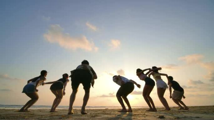 日落时分，朋友们在海滩上跳跃的剪影带着快乐的情感。4k分辨率。慢动作镜头。