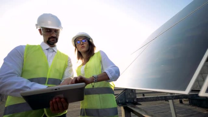 两名工人检查太阳能电池板，站在屋顶上，关闭。