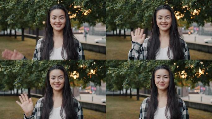 在公园里，年轻的亚洲妇女挥舞着微笑着看着相机的慢动作