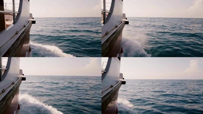 相机在阳光明媚的日子里，在深蓝色的大海中航行的邮轮游艇的右侧，有惊人的泡沫白浪。