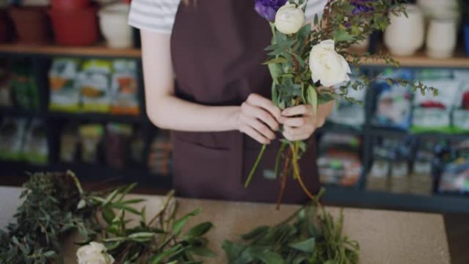 年轻女子花店在商店布置美丽的花朵制作构图