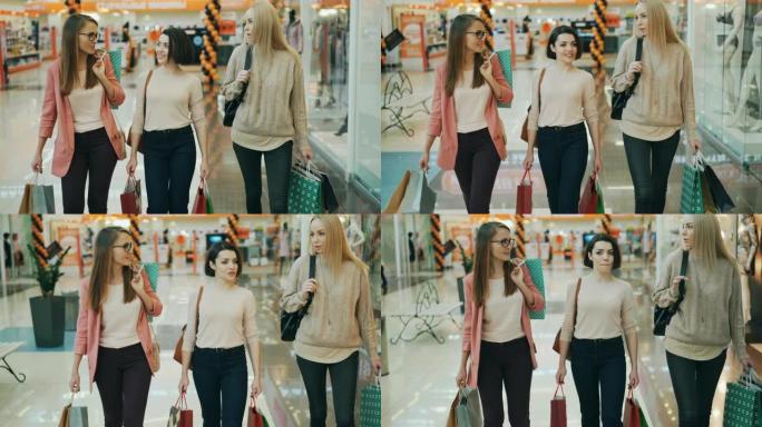 漂亮的年轻女性在购物中心里背着纸袋购物时聊天。零售、快乐顾客和青年生活理念。