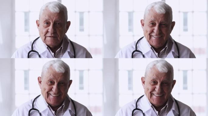 头部照片微笑的80岁成熟的主治医生看着相机。