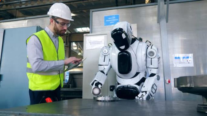 一个人在平板电脑上打字，而机器人则使用工厂细节。