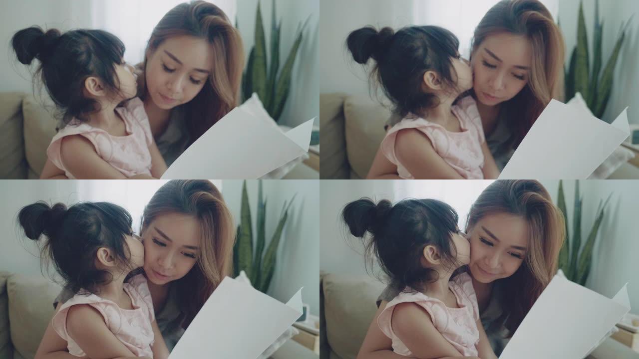 亚洲妇女在母亲节阅读明信片并与女儿微笑