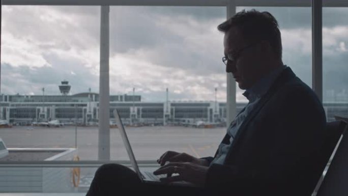 商人在机场等候时使用笔记本电脑