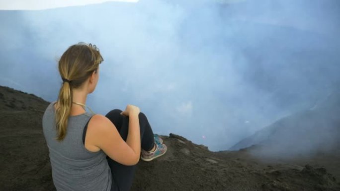 特写: 无法识别的女性旅行者坐在活火山的边缘。