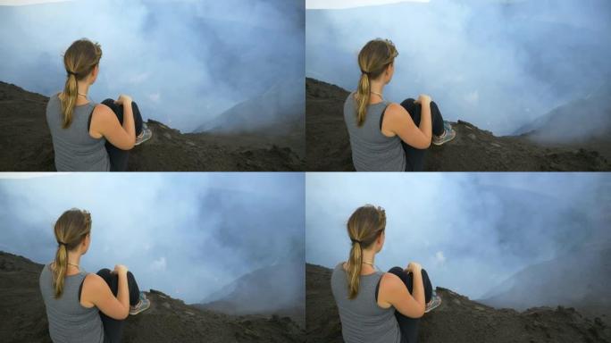 特写: 无法识别的女性旅行者坐在活火山的边缘。