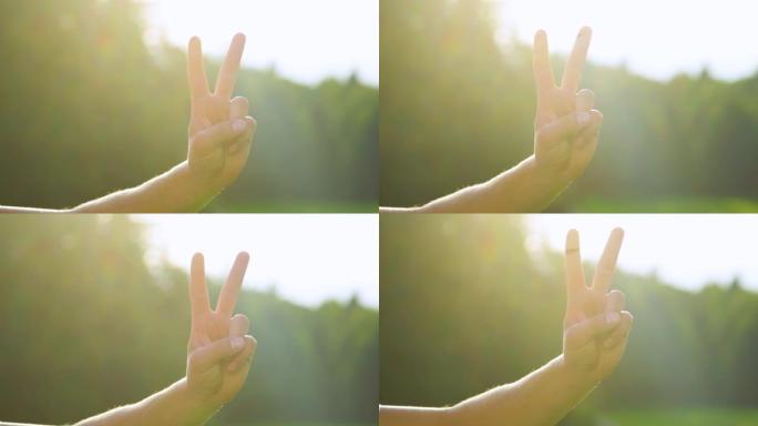 慢动作: 明亮的阳光照射在男性手上，并显示出和平标志。