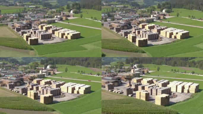空中: 汽车驶向村庄，经过阳光明媚的奥地利的一家大型锯木厂