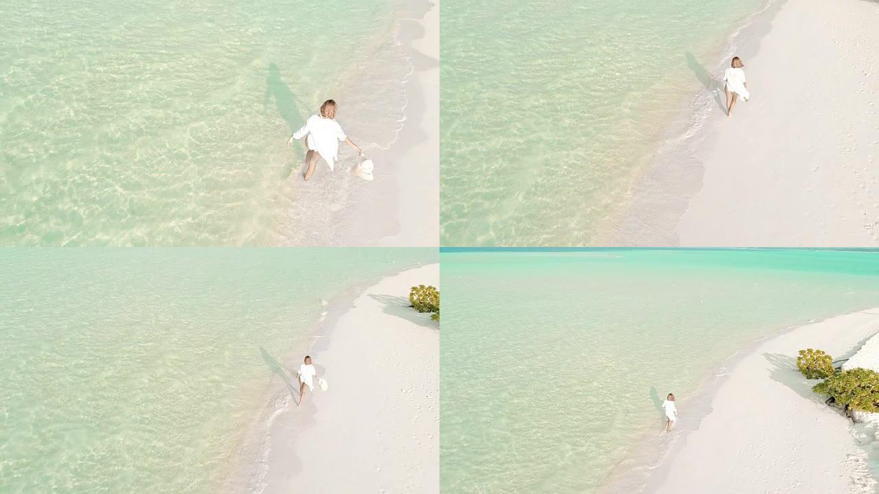 女士在马尔代夫阳光明媚的田园诗般的热带海滩上行走