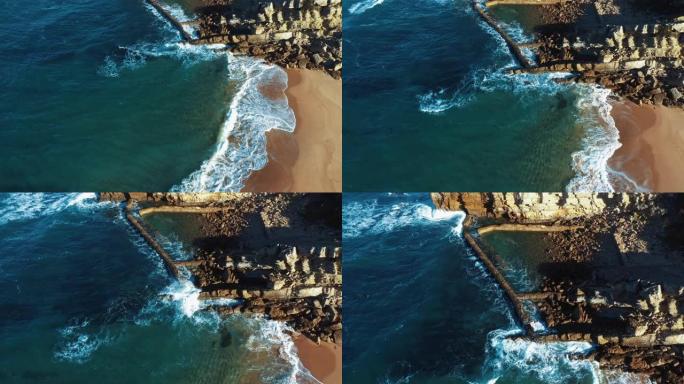 自上而下的空中无人机镜头: 葡萄牙岩石海岸，美丽的海景。抽象自然，海岸线上碧绿的海浪在沙滩上滚动。P