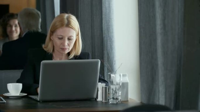 在餐厅使用笔记本电脑的高级商务女士