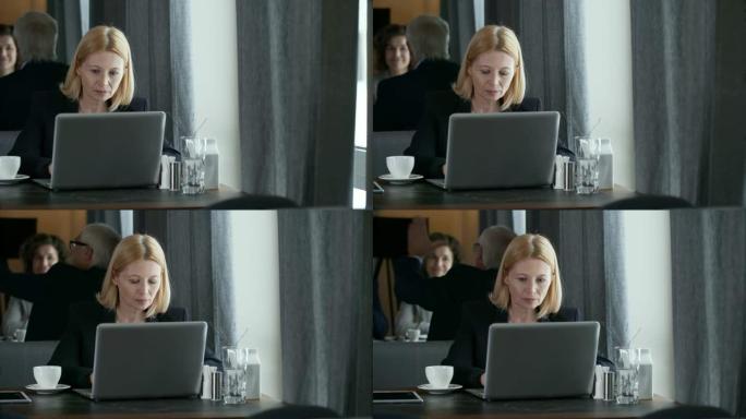 在餐厅使用笔记本电脑的高级商务女士