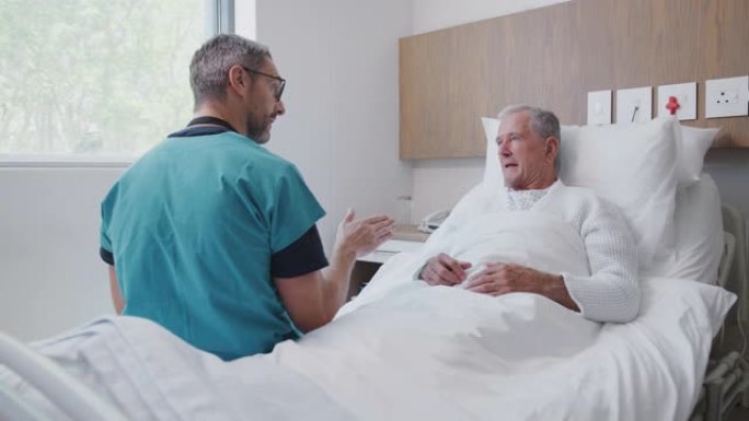外科医生在老年病室的病床上拜访并与资深男性患者交谈