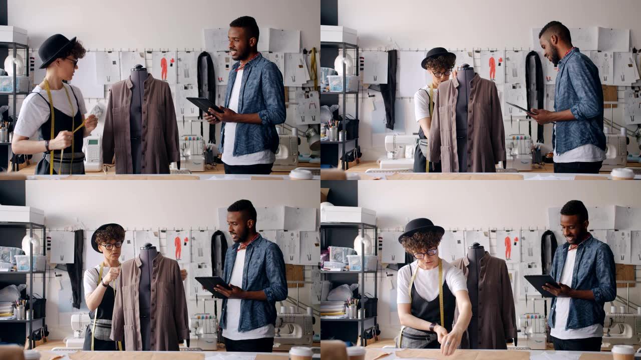 裁缝在同事使用平板电脑交谈时在假人上测量服装