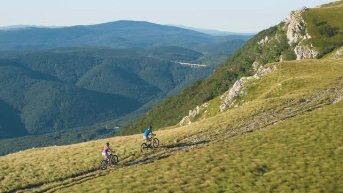 空中: 男女骑自行车的人沿着风景优美的小径踩踏自行车。