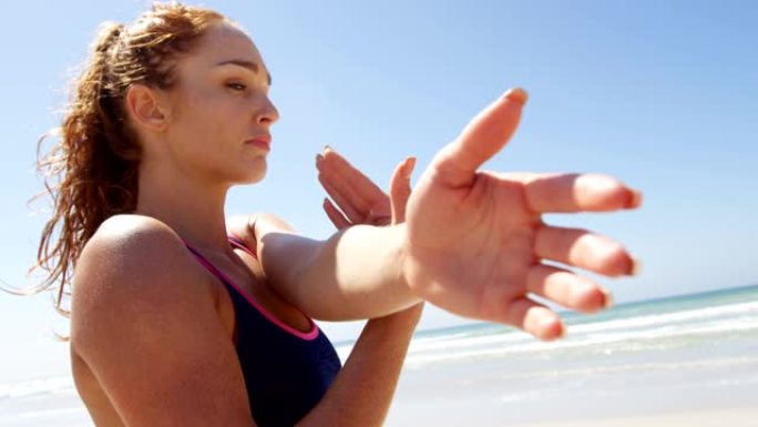 女人在阳光明媚的日子在海滩上锻炼4k