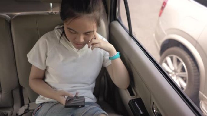十几岁的女孩在购物中心等待母亲购物时在车里使用智能手机