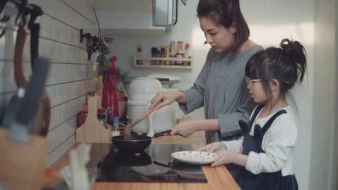 可爱的小女孩和妈妈在家做饭