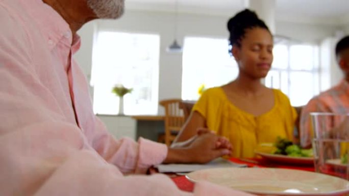 多代黑人家庭在舒适的家庭4k餐桌上一起祈祷