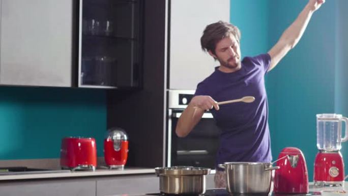 一个穿着睡衣的男人在厨房里唱歌跳舞，手里拿着勺子混合食物。