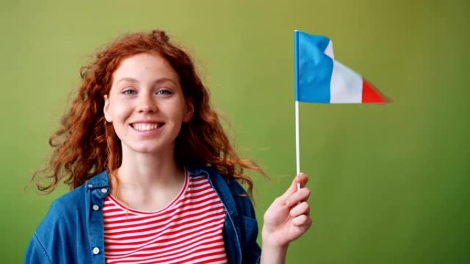 美丽的少女手持法国国旗微笑着看着相机