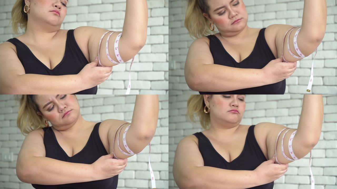 超重的女人测量她的手臂