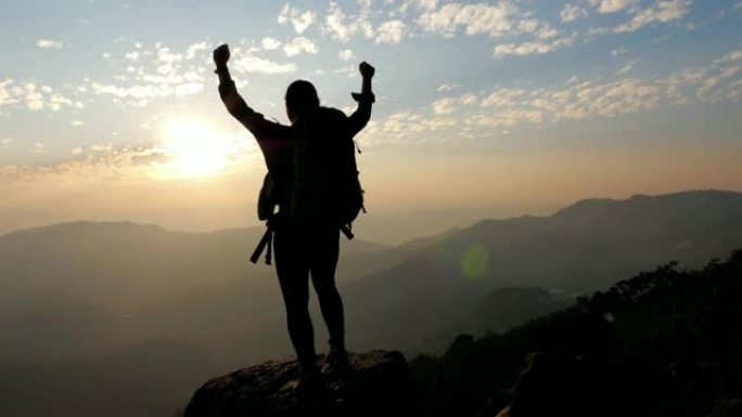 女人徒步到山顶，举起手来庆祝成功，慢动作