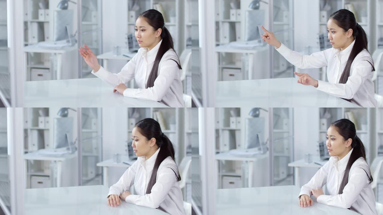年轻的亚洲女性在办公室里看着隐形的AR触摸屏