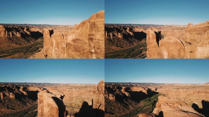 无人机飞越巨大的岩石，揭示了阳光明媚的岩石沙漠中峡谷山脊之间的宏伟公路。