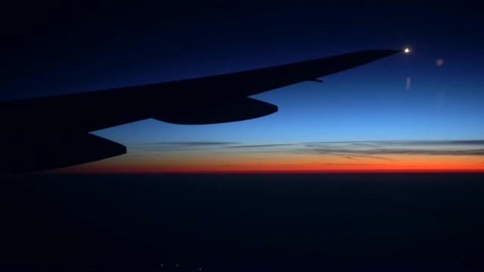 美丽的日出或日落。天空中的飞机和云的翅膀