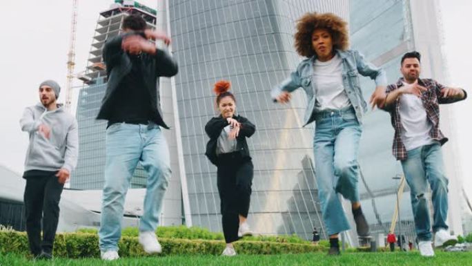 一群不同种族的年轻城市舞者的慢动作很高兴在摩天大楼的市中心进行训练