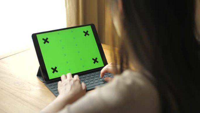 女人使用带键盘的绿屏平板电脑