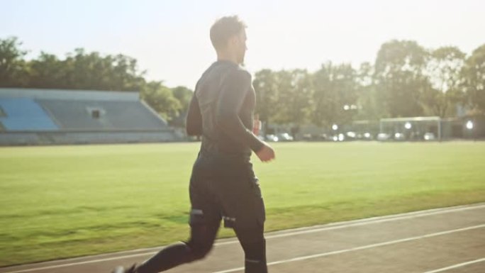 穿着灰色衬衫和短裤的运动健美男子在体育场慢跑。在一个温暖的夏日下午，他正在舒适地跑步。运动员做他的常