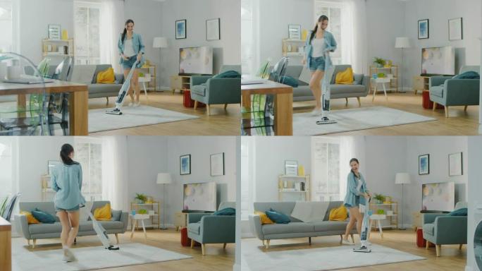 穿着牛仔裤衬衫和短裤的年轻美女正在家里明亮舒适的房间里跳舞和真空清洁地毯。她使用现代无绳真空吸尘器。