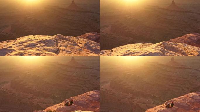 在美国犹他州死马角州立公园，两名面目全非的女性游客坐在悬崖边享受温暖的日落。Steadicam sh