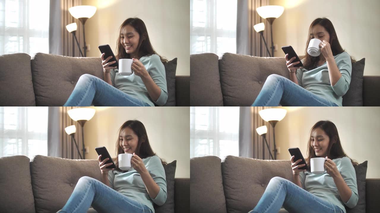年轻的亚洲妇女坐在沙发上，在家中使用手机