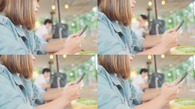 商业自由亚洲女性坐在咖啡馆的桌子上时，使用智能手机聊天，阅读和发短信。生活方式聪明的美女在咖啡店工作