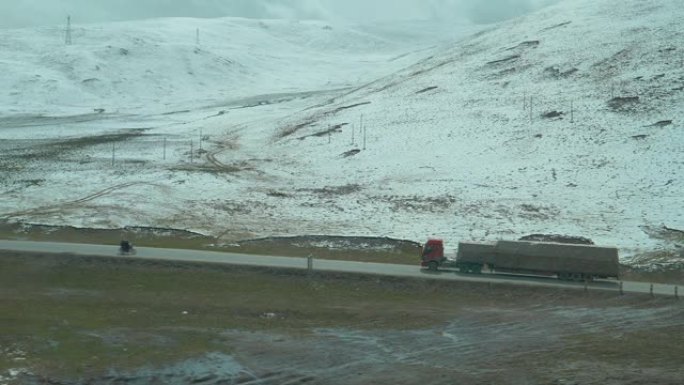 天线: 大型货运卡车在穿越雪域藏族平原的道路上行驶。