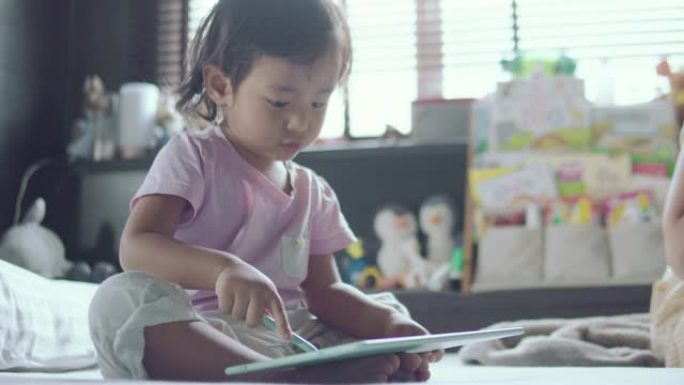儿童坐在床上用数字平板电脑画画。