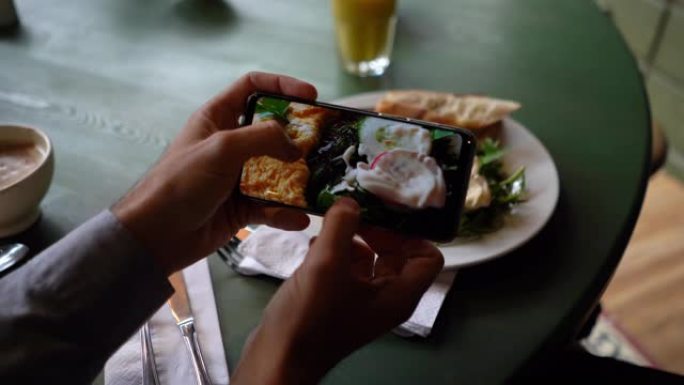 面目全非的男子在一家面包店用智能手机放大拍摄美味早餐的照片
