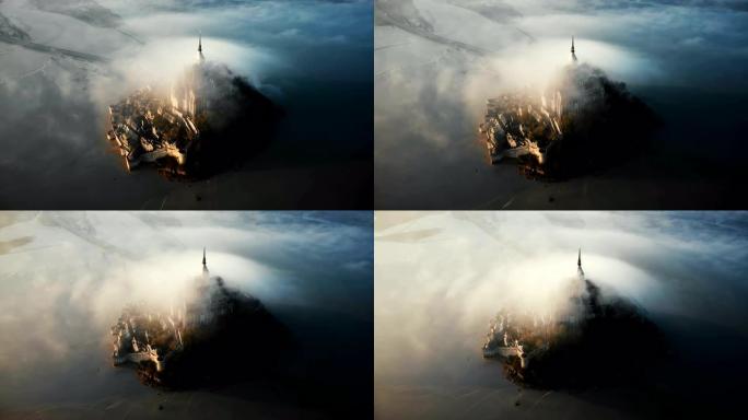 无人驾驶飞机在令人惊叹的圣米歇尔山城堡堡垒周围高飞，覆盖着巨大的日出雾云。