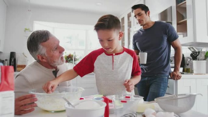 十几岁的西班牙裔男孩和他的祖父和父亲在家里的厨房里做蛋糕，特写