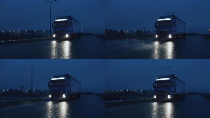 满载货物拖车的长途半卡车在夜间在高速公路上行驶，穿过雨、雾、雪穿越大陆。工业仓库区。慢动作拍摄后的正