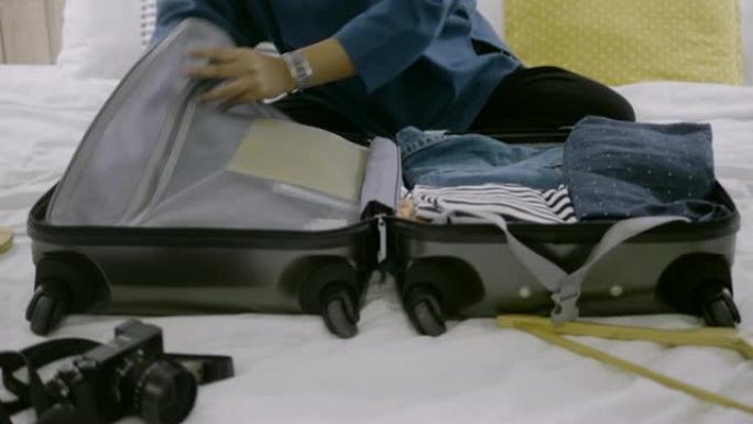 亚洲女性在床上打包行李箱