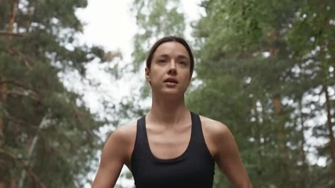 运动的年轻女子沿着森林路奔跑