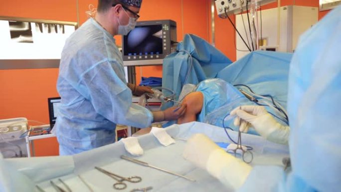 男性外科医生在处理患者膝盖时使用带摄像头的工具。